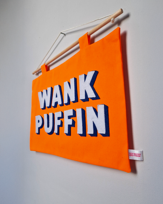 Orange pennant sweary wall art saying Wank Puffin cheeky home decor on a grey wall